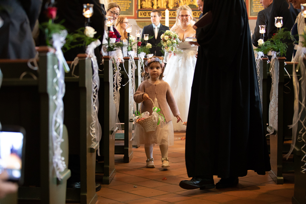 Blumenmädchen läuft in der St.Willibrord Kirche in Neetze vor der Braut