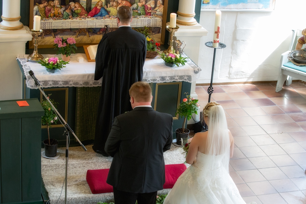 Hochzeitspaar steht hinter dem Pastor am Altar in der St Lamberti-Kirche in Nahrendorf